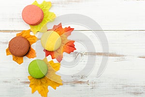 Macaroni cakes and autumn leaves on a wooden background