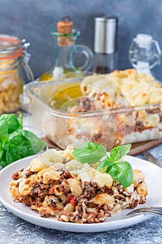 Macaroni casserole with ground beef, cheese and tomato on  plate, vertical