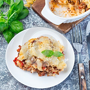 Macaroni casserole with ground beef, cheese and tomato on plate, vertical, top view, square format