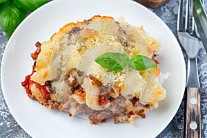 Macaroni casserole with ground beef, cheese and tomato on a white plate, horizontal,  top view, closeup