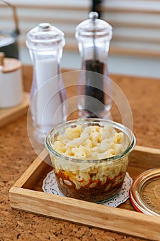 Macaroni Cheese Baked with meat sauce in glass bowl on wooden plate with salt, pepper and cutlery