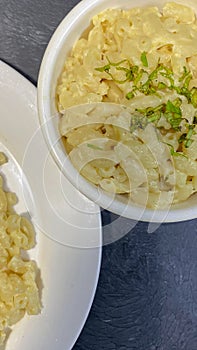 Macaroni cheese in a white bowl, on a black background.