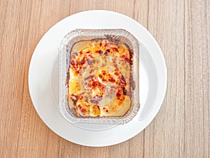 Macaroni with ham and cheese in a baking dish on wooden table. Top view