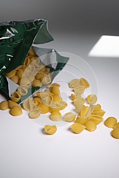 Macaroni in a package on a white background with shadows.