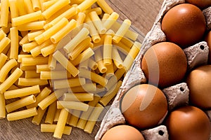 Macaroni Pasta and fresh eggs on wooden table