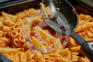 Macaroni and tomato sauce ready to serve. Image of prepared catering food at the time of serving the dishes