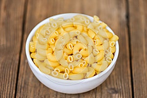 Macaroni top view on bowl and wooden background - close up raw macaroni uncooked delicious pasta or penne noodles