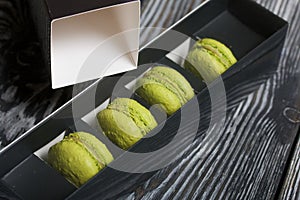 Macarons cakes light green color. Packaged in a black box. On black and white pine boards