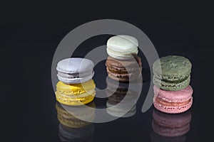 Macarons concept in complementary colors on black background with reflection