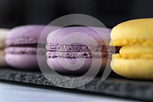 Macarons are laid out on a black slate in beautifully colored rows.