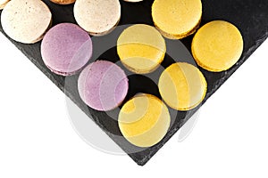 Macarons are laid out on a black slate in beautifully colored rows.