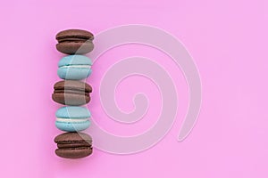 Macarons macaroni cookies. Biscuits, chocolate and turquoise colors. Cake with cream filling on a pink background.