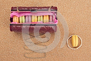 Macarons in shiny fashion handbag on gold.Vintage