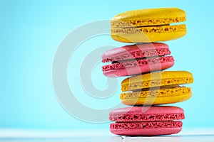 Macaroon cake red and yellow on a white wooden table on a blue