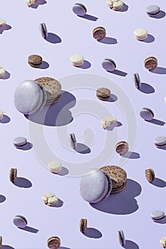 Macaroon patern of different sizes, chocolate, coconut and berry cookies on a lilac, purple background