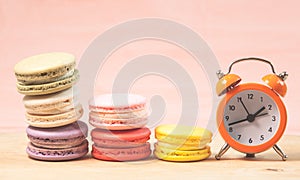 Macaroons and alarm clock on table, vintage stylized photo