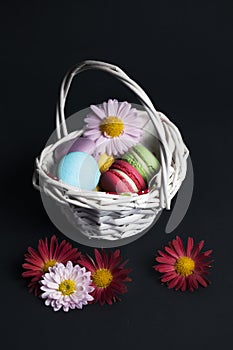 Macaroons in the basket on black background