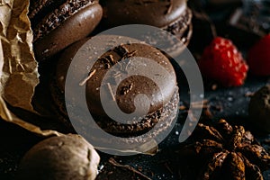 Macaroons with berries, chocolate and badiane on a black background