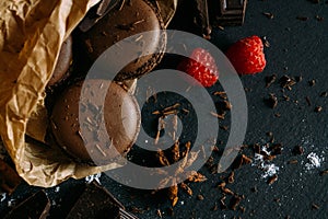 Macaroons with berries, chocolate and badiane on a black background