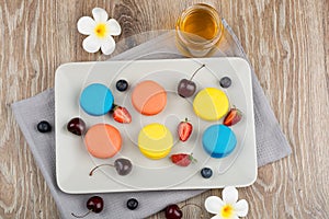 Macaroons and berries on wooden background