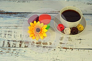 Macaroons, coffee, baals and flower on a table.