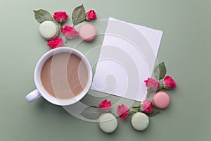 Macaroons, coffee and rose on green background. Top view. Flat lay