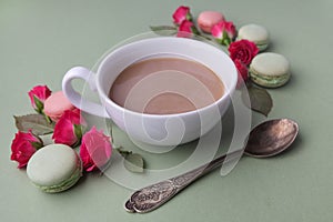 Macaroons, coffee and rose on green background. Top view. Flat lay