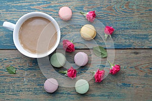 Macaroons, coffee and rose on green wooden background. Top view. Flat lay