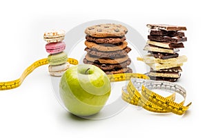 Macaroons, cookies, chocolate bars, apple and measuring tape