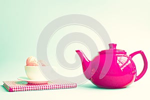 Macaroons in a cup over book and red teapot