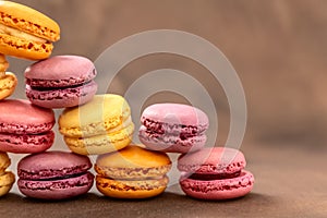 Macaroons. Multicolored Macaroons on a brown background. Pyramid. Pink, yellow and red Macaroons. French cake. Place for