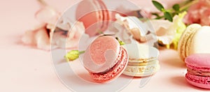 Macaroons in pastel colors with flowers on a pale pink background.Holiday background