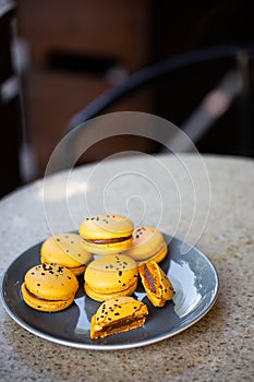 Macaroons on a plate on a gray background. French macarons isolated. Selective focus. Beautiful yellow macaroons with