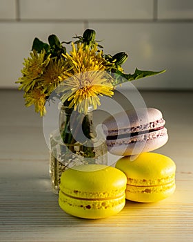 Macaroons and a vase of yellow dandelions.