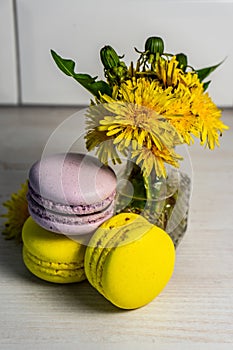 Macaroons and a vase of yellow dandelions.