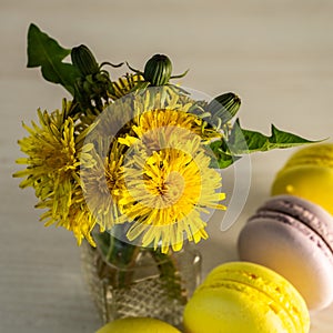 Macaroons and a vase of yellow dandelions. Selective focus.