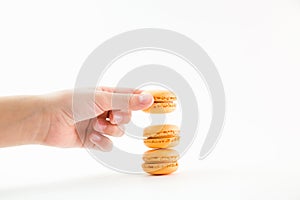 Macaroons on a white background and hand holding one and folding them into a tower, colorful macaroons, selective focus