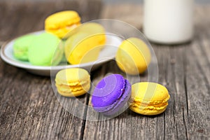 Macaroons on wood table with obe bottle of milk