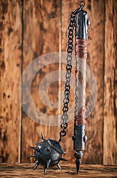 Mace with a stick and spikes on a wooden background.