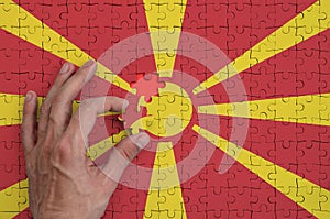 Macedonia flag is depicted on a puzzle, which the man`s hand completes to fold