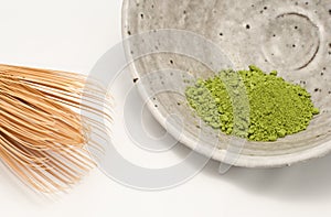 Macha green powder in a bowl, with the whisk