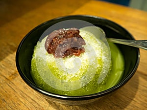 Macha green tea shaved ice with red beans. Traditional Japanese sweet Dessert in black bowl