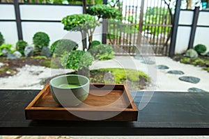 Macha green tea on wooden table with Japanese garden