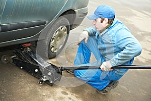 Machanic repairman at tyre fitting with car jack
