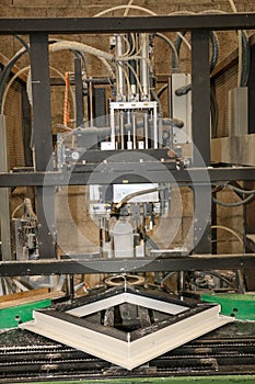 A machine assembles a PVC window frame in a carpentry photo