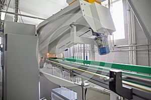 Machine for blowing plastic bottles from PET preforms, industrial conveyor belt in factory interior