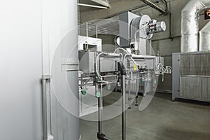 Machine for blowing plastic bottles from PET preforms, industrial conveyor belt in factory interior