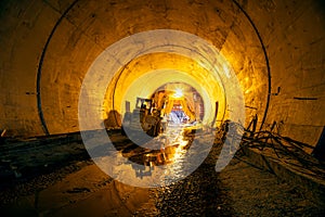 Machine on construction place of building new railway tunnel, illuminated by yellow light