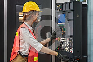 Machine control worker at control panel operating CNC lathe machine in metalwork workshop