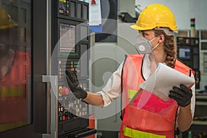 Machine control worker at control panel operating CNC lathe machine in metalwork workshop